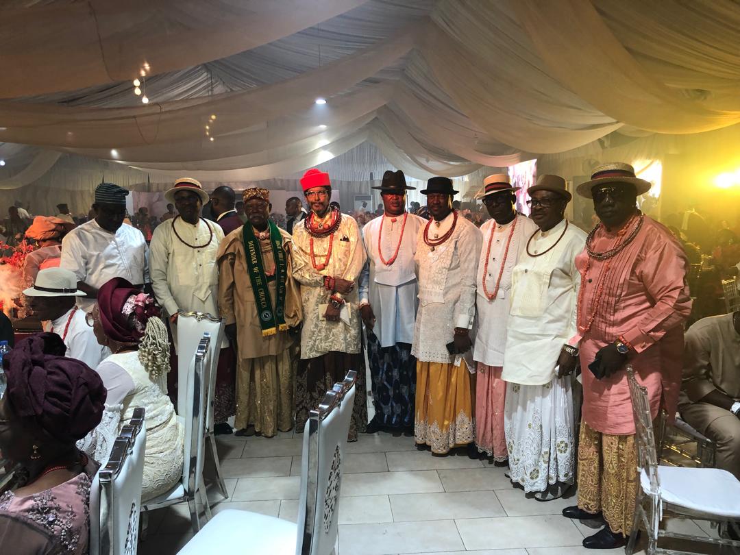 Nine distinguished Urhobo chiefs in traditional white regalia and red beads, standing together at a major Urhobo community gathering