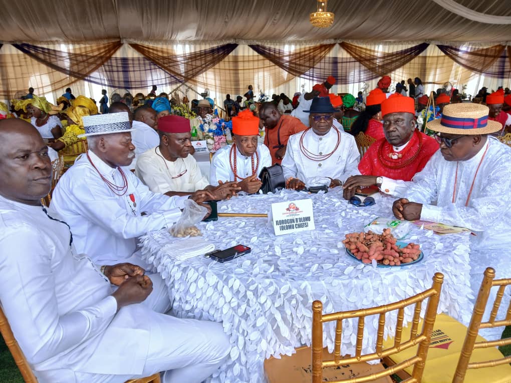 Ilorogun r'Olomu (Olomu Chiefs) seated together in traditional white regalia and red beads at a major Urhobo community gathering
