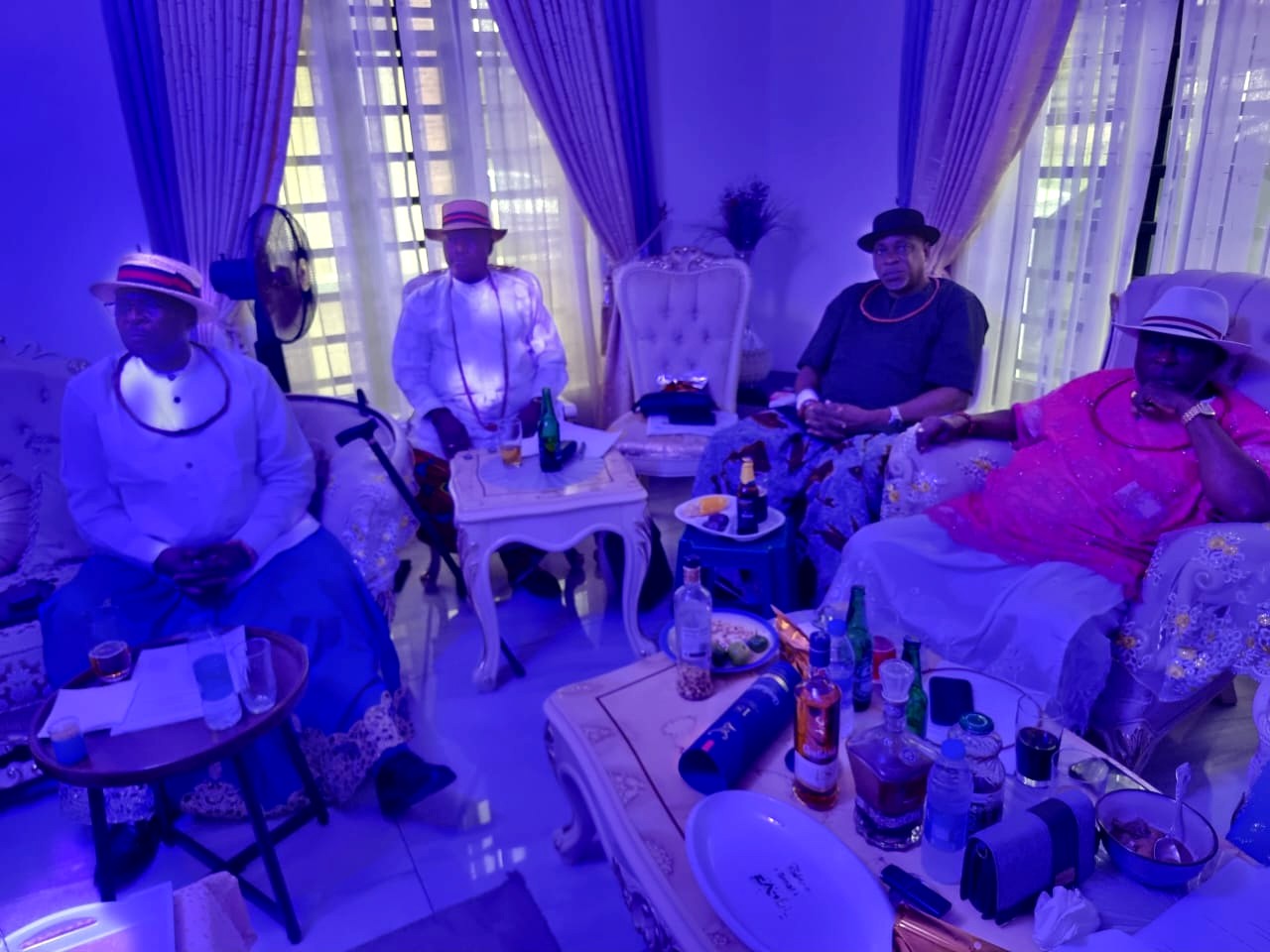 Four Urhobo Social Club Lagos members in traditional Urhobo regalia seated on a white sofa