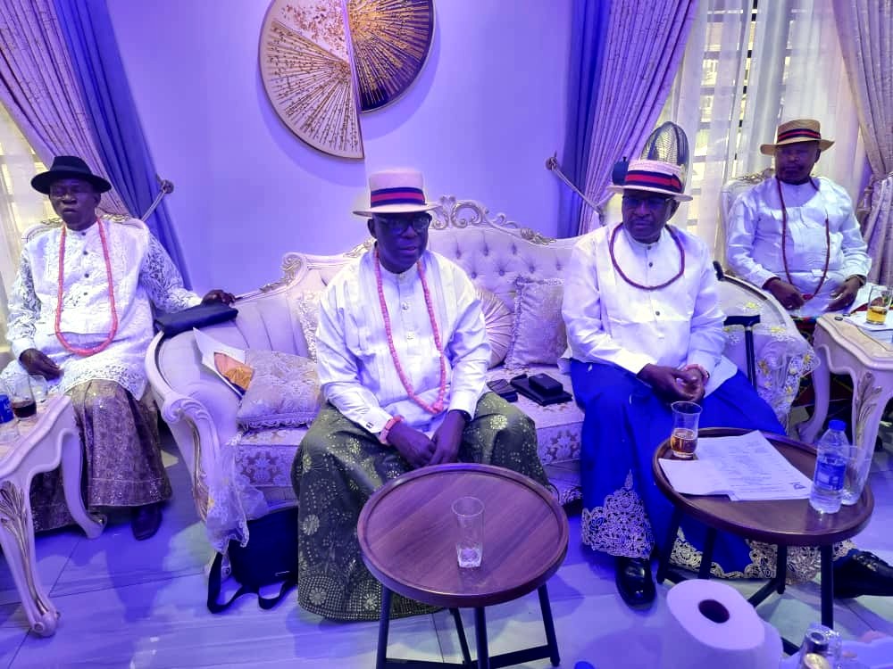 Four members of the Urhobo Social Club Lagos in traditional white tops and red beads, seated together at a club gathering